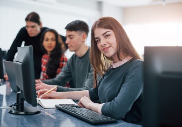 Pretty girl. Group of young people in casual clothes working in the modern office.